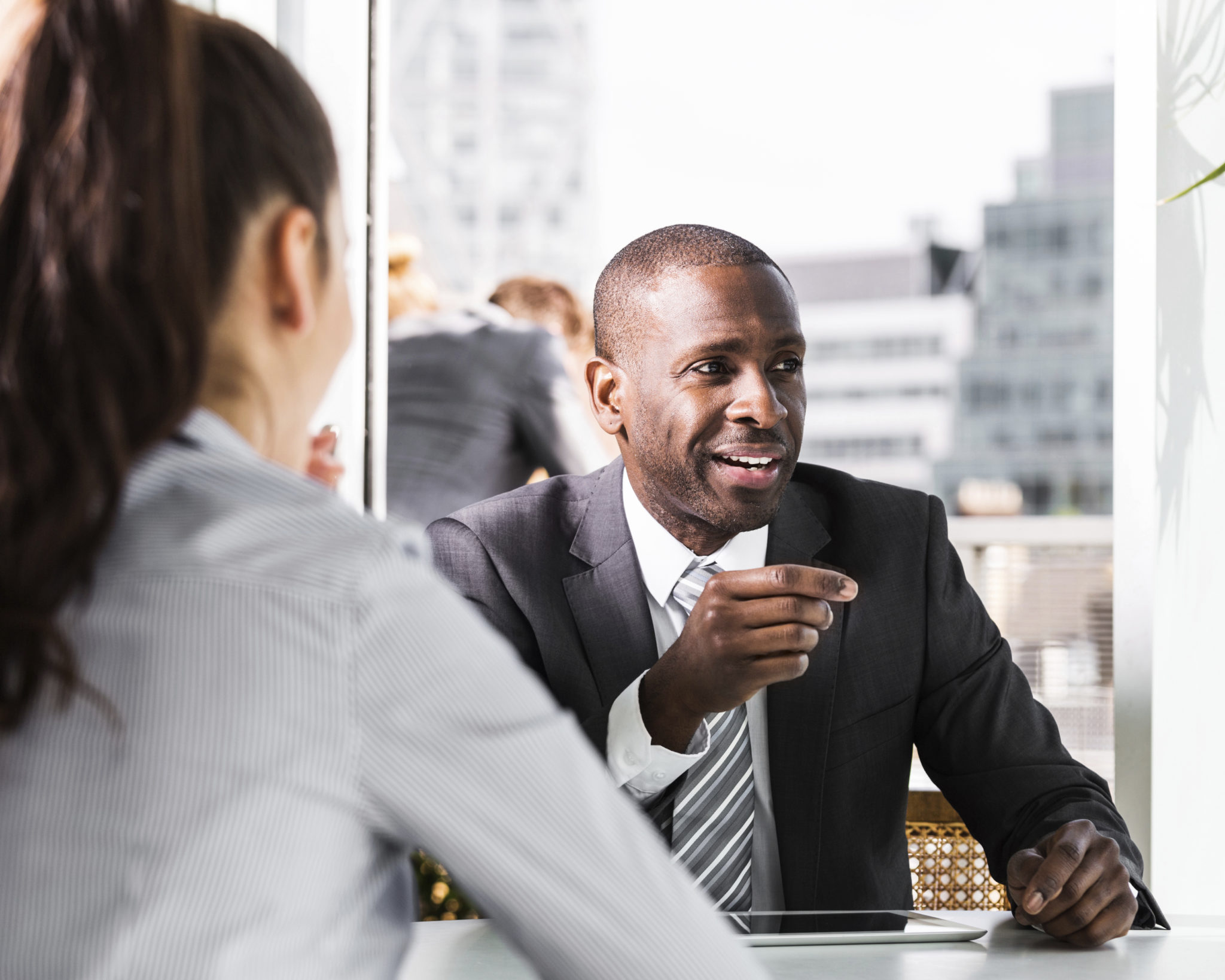 businessman smiles away from camera as he talks to a woman